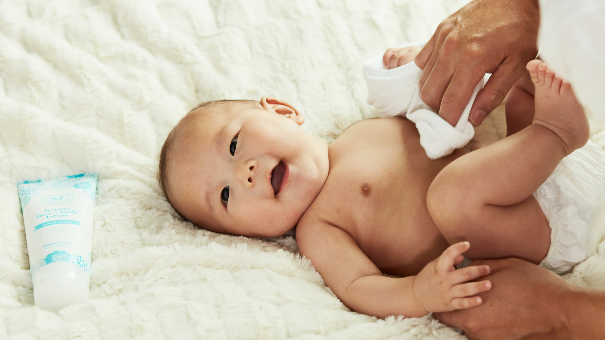 baby in diaper lying on bed